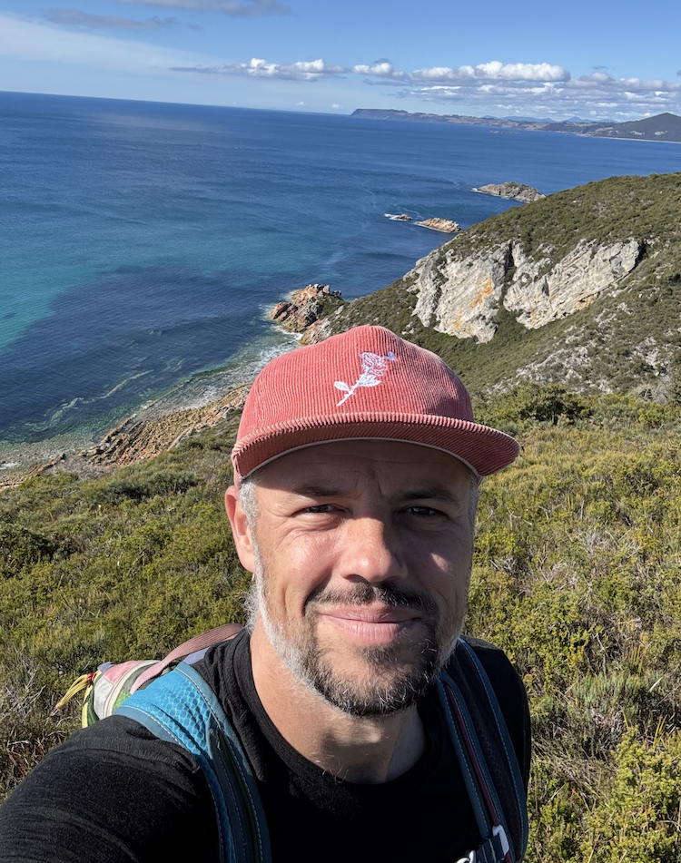 Yvan smiling on a coastal walking track above the sea